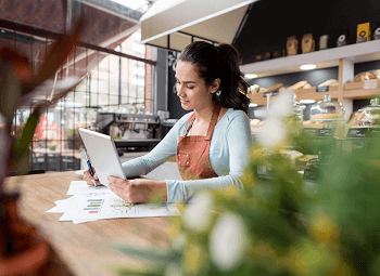 Woman small business owner reviews something on a tablet in her cafe